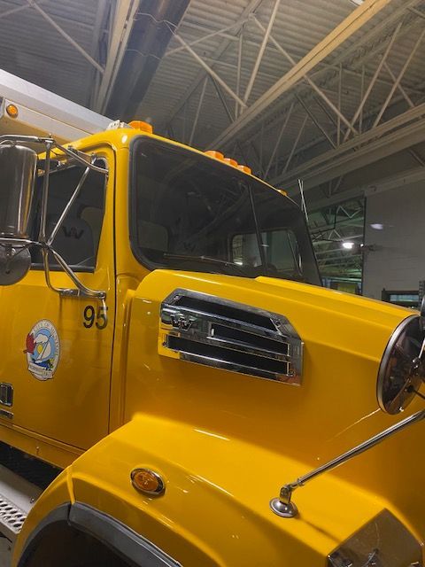 Yellow truck with chrome grill and insignia, parked indoors.