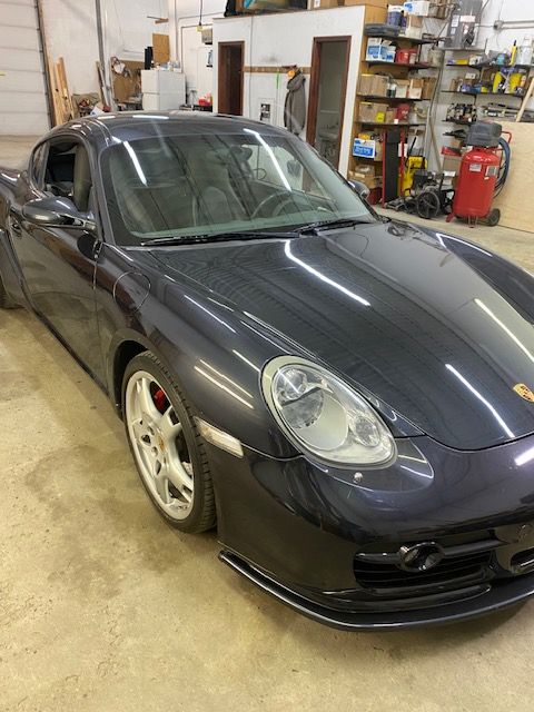 Dark gray Porsche coupe parked inside a garage.
