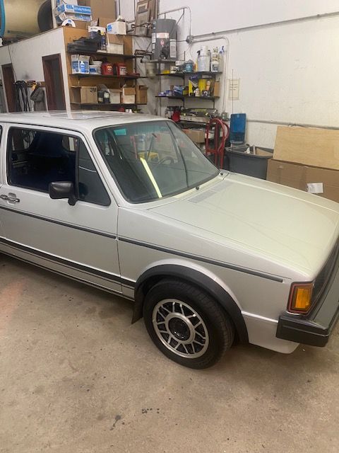 Silver Volkswagen Golf parked in a garage, featuring black rims and trim.