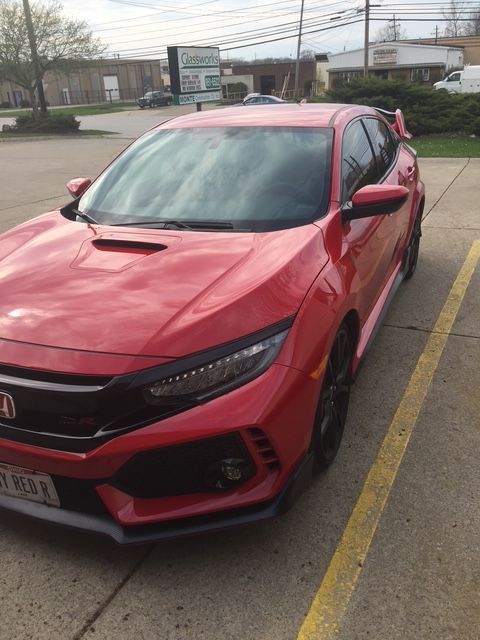 Red Honda Civic Type R parked on concrete, black accents, hood scoop, parking lines visible.