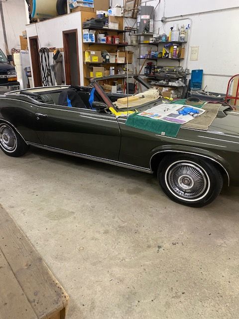 Dark green convertible car inside a workshop.