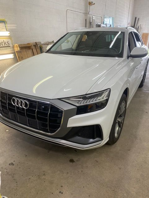 White Audi Q8 SUV parked indoors with a gray grill and black accents.