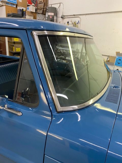 Blue vintage truck cab with chrome trim around the windshield.