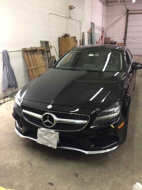 Black Mercedes-Benz sedan parked in a garage; glossy black paint, chrome accents, and a bright interior.