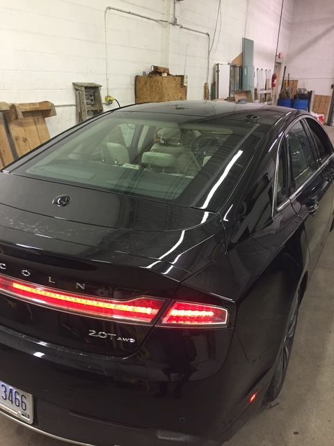 Black Lincoln MKZ sedan in a garage. Tail lights are on.