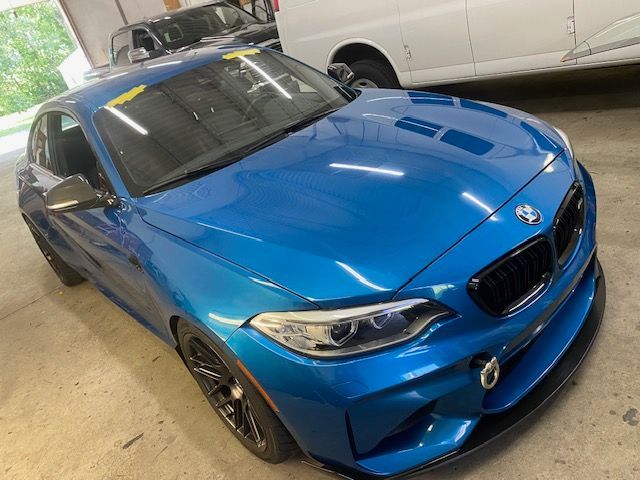 Blue BMW M2 sports car parked inside a garage, close up.