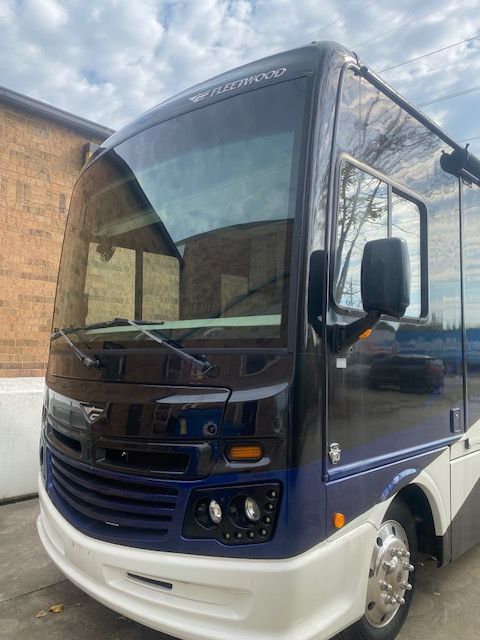 Blue and white RV parked outside a building with a brick wall.