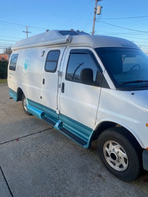 White camper van with teal trim parked outdoors.
