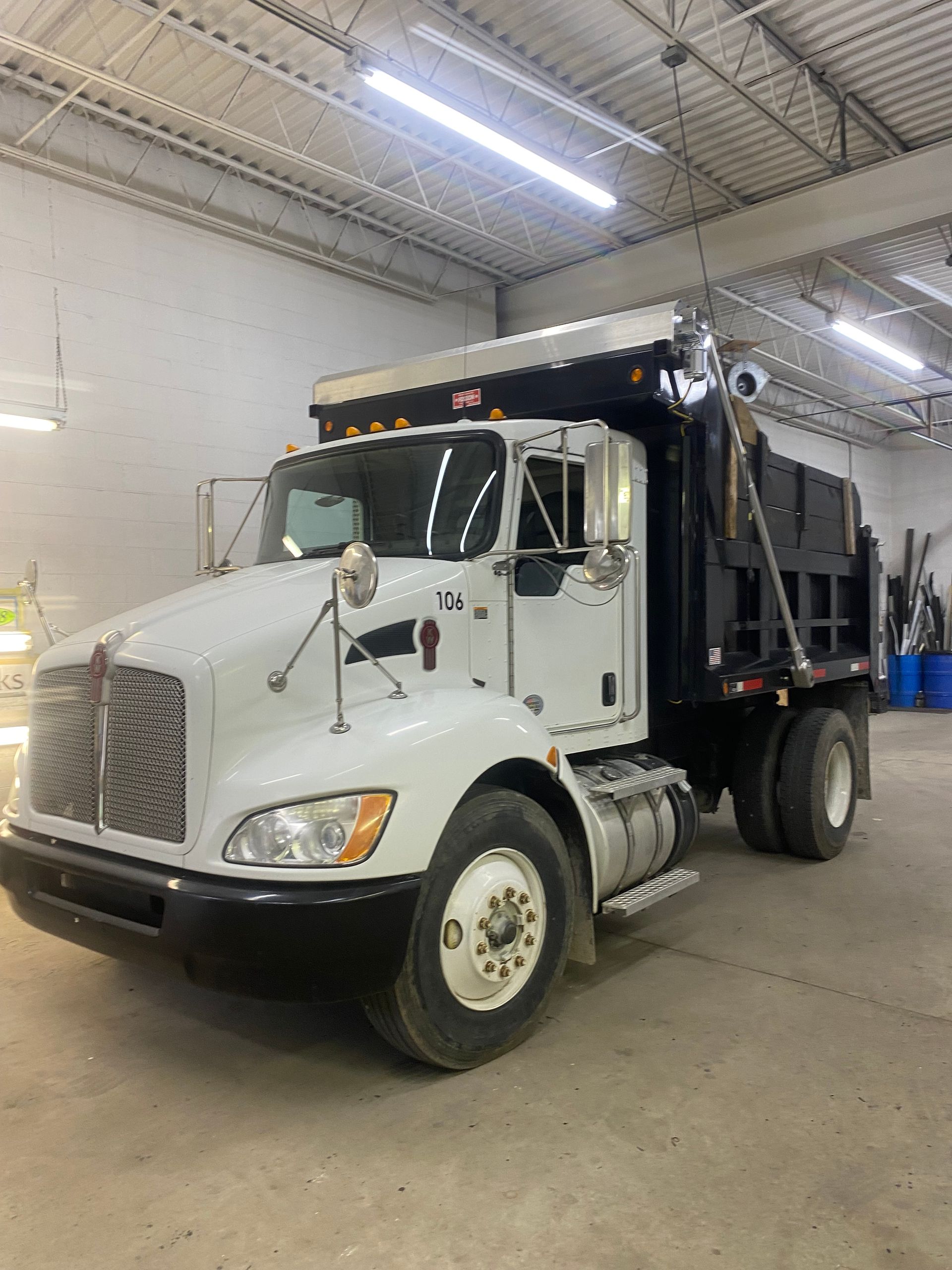 White Kenworth dump truck inside a garage.