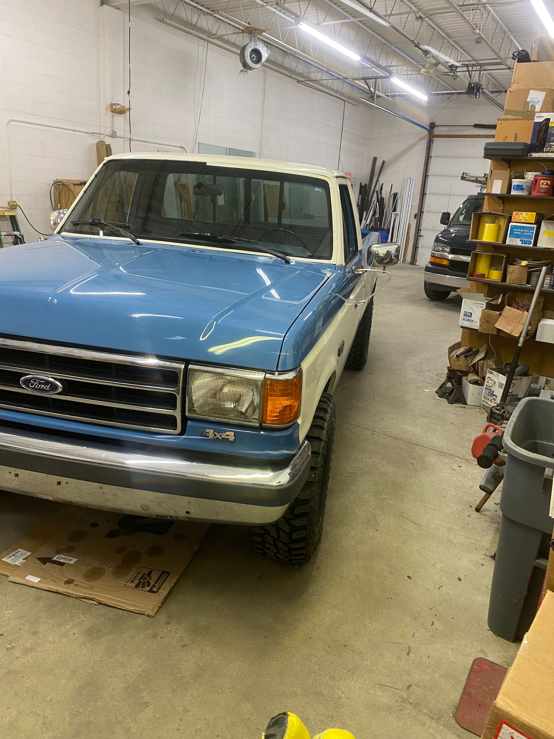 Blue and white Ford pickup truck inside a garage.