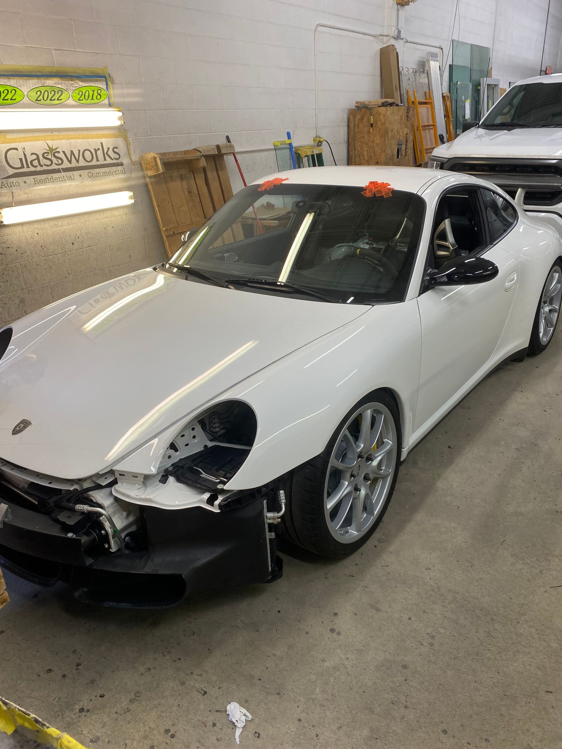 White Porsche sports car, front end damaged in a repair shop.