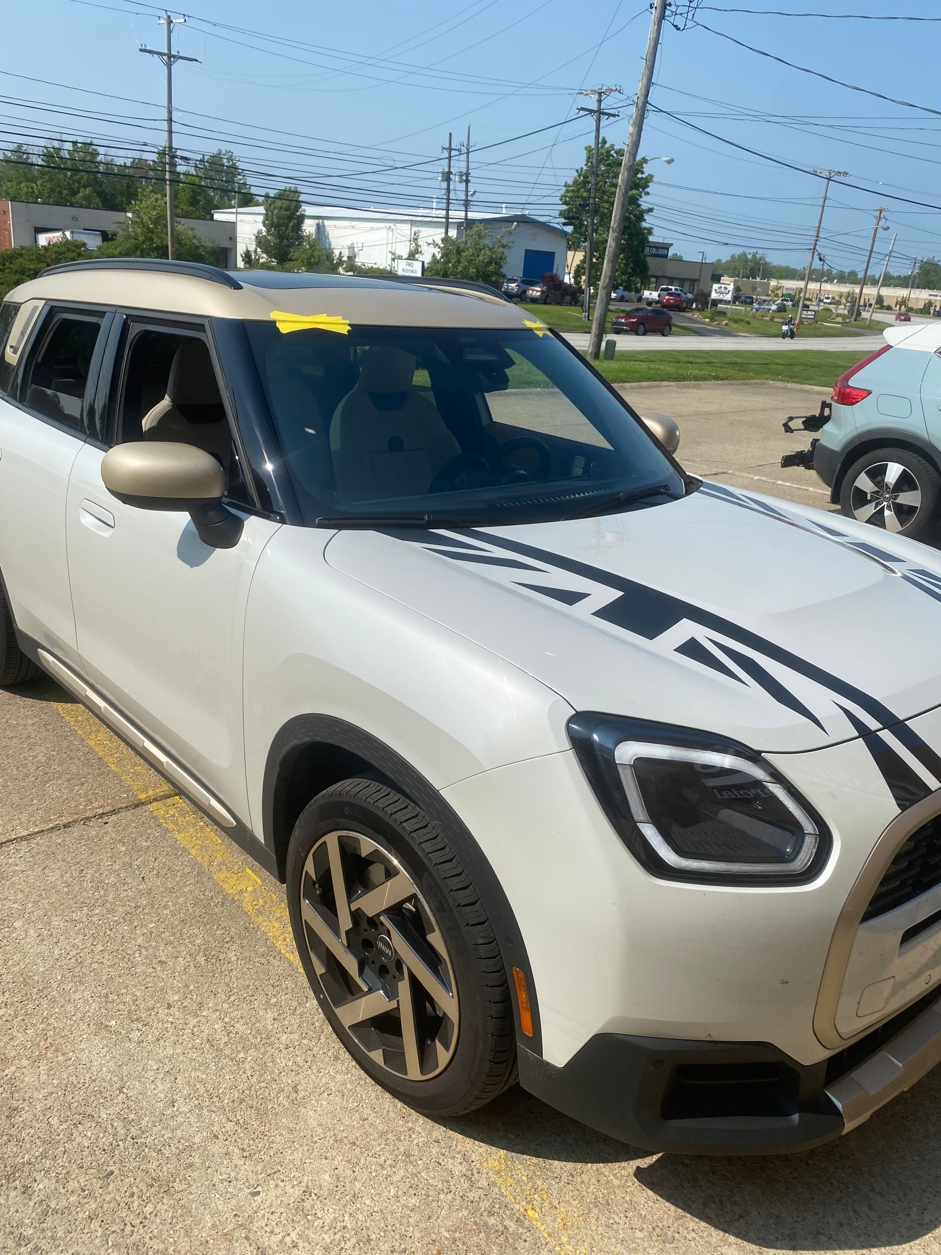 White SUV with black accents and gold wheels parked outside on a sunny day.