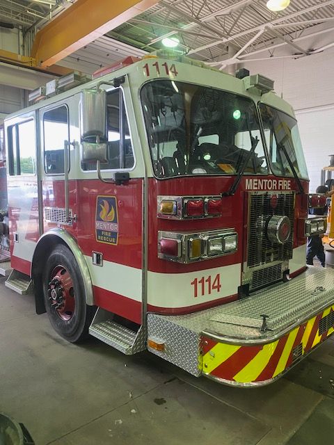 Fire truck, red and white, marked 1114, from Mentor Fire, parked in a garage.
