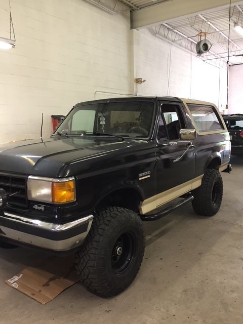 Black Ford Bronco with tan accent parked in a garage.