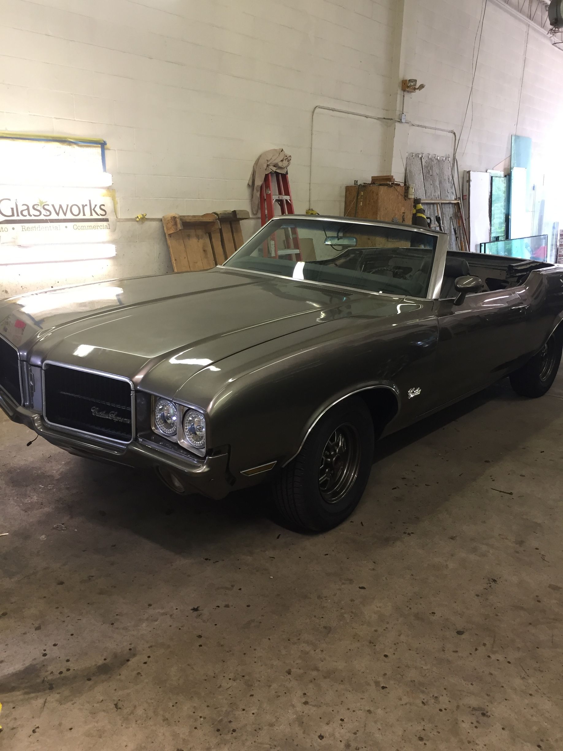 Raindrops on a window, blurred, with a circular object visible behind the glass. Dark teal and grey tones.