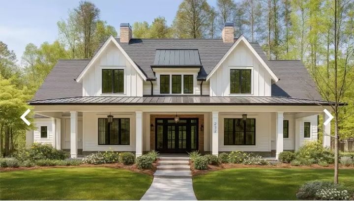 White farmhouse with black trim, porch, and gray roof, set in a grassy yard with trees.
