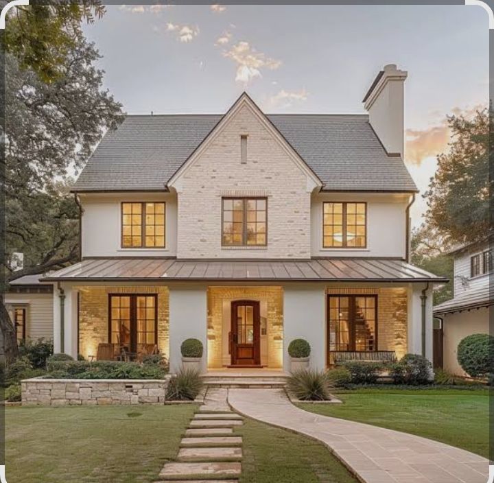 Two-story house with white stucco, brick accents, and a porch, at sunset.