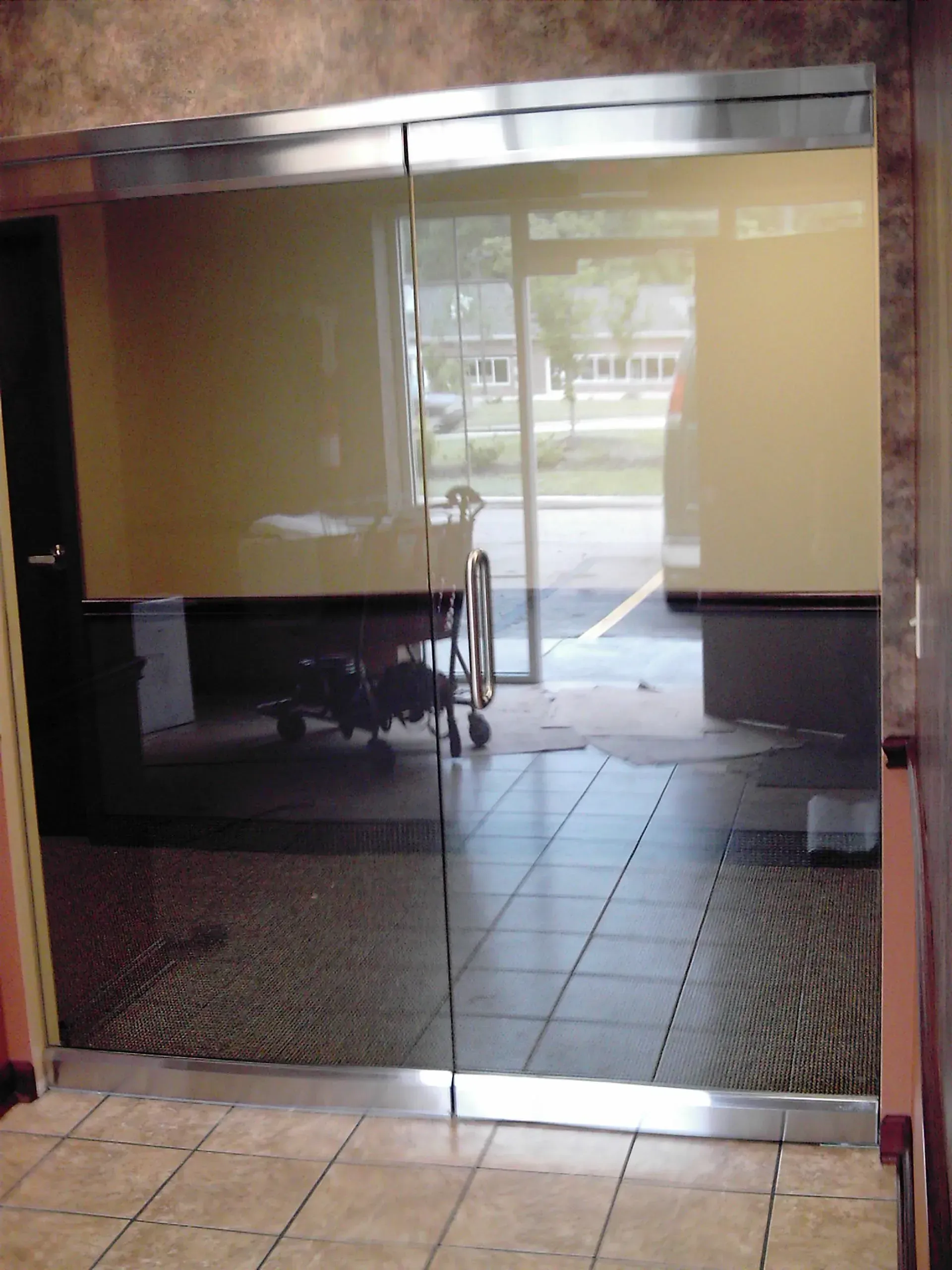Glass doors lead outside, reflecting a parked wheelchair and buildings beyond.