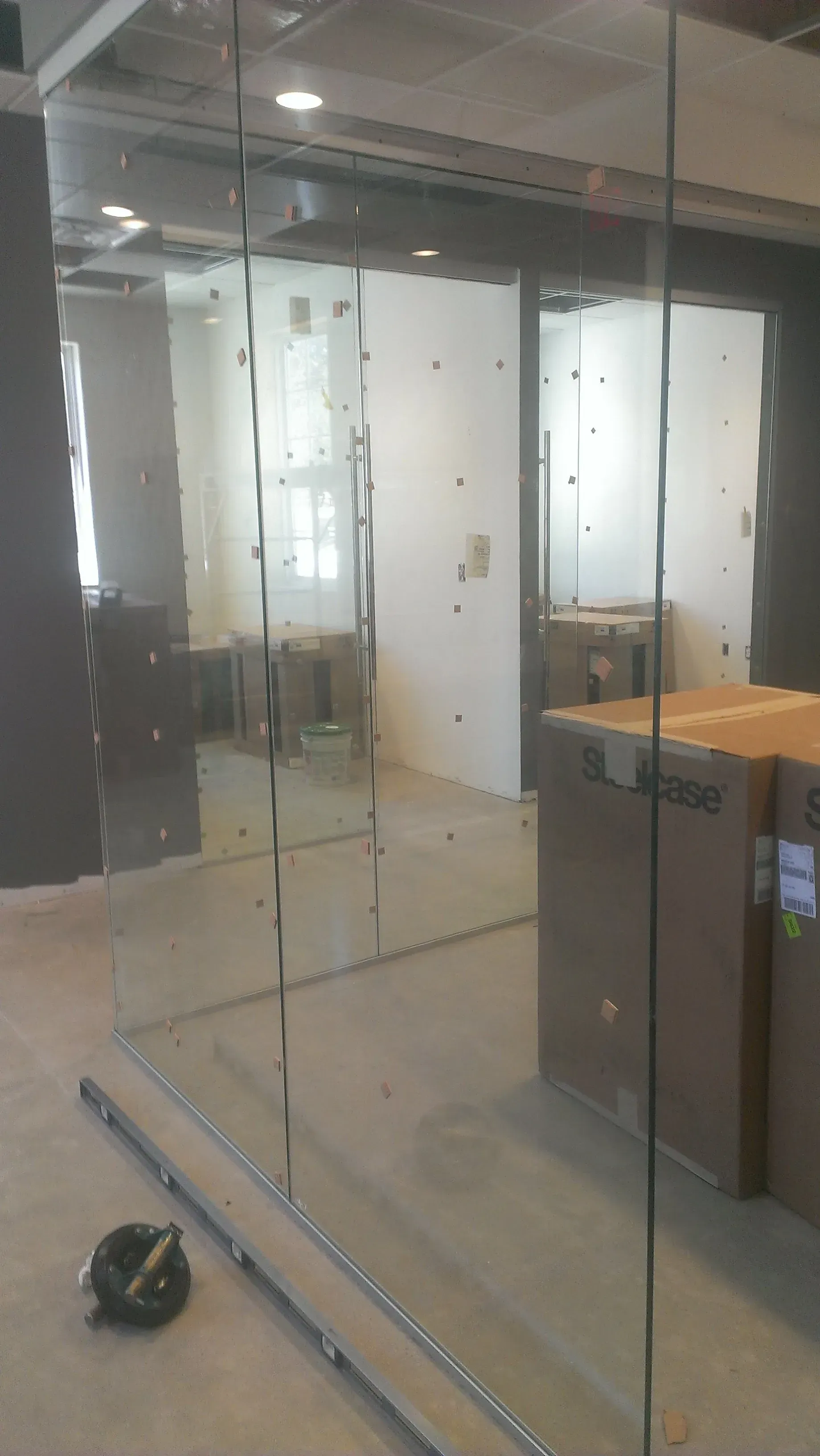 Glass-walled office space with boxes and unfinished walls.