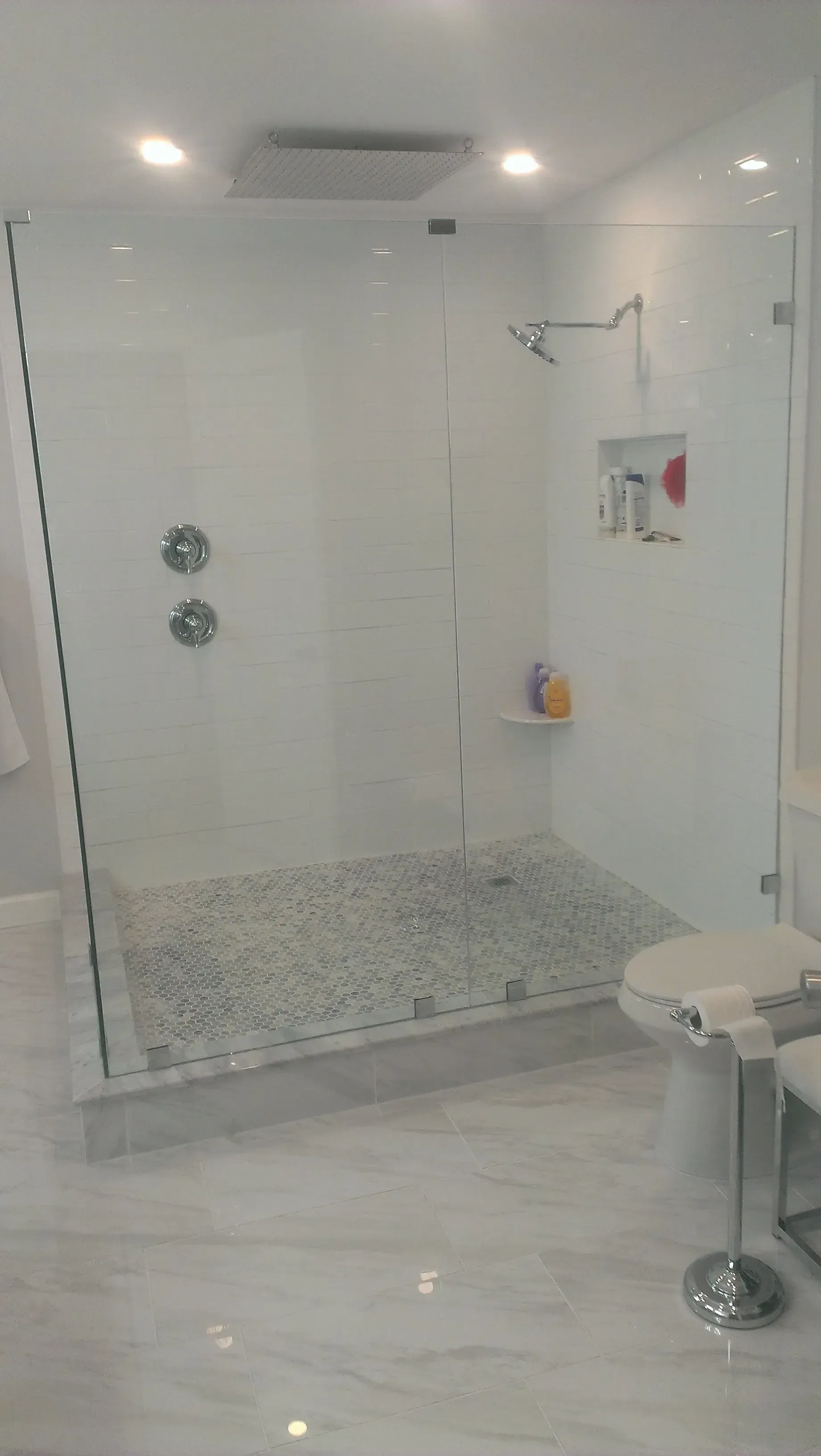 Modern bathroom with glass shower, tiled floor, and shower seat.