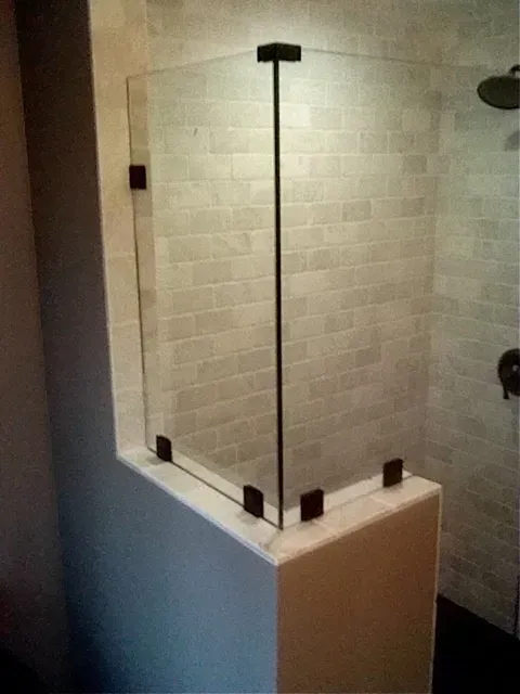 Glass shower enclosure with black hardware in a tiled bathroom.