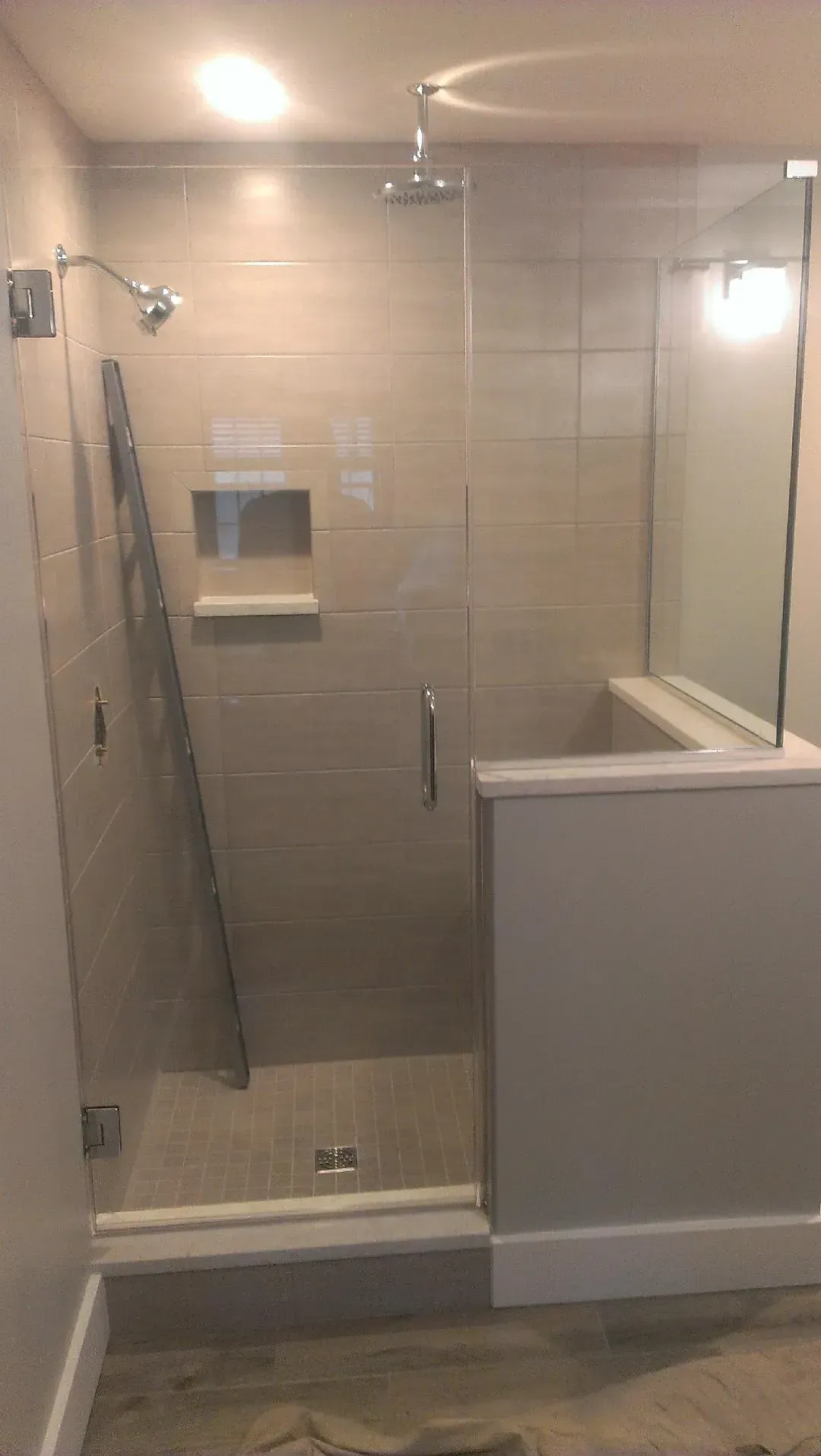 Modern shower stall with glass doors and beige tile.