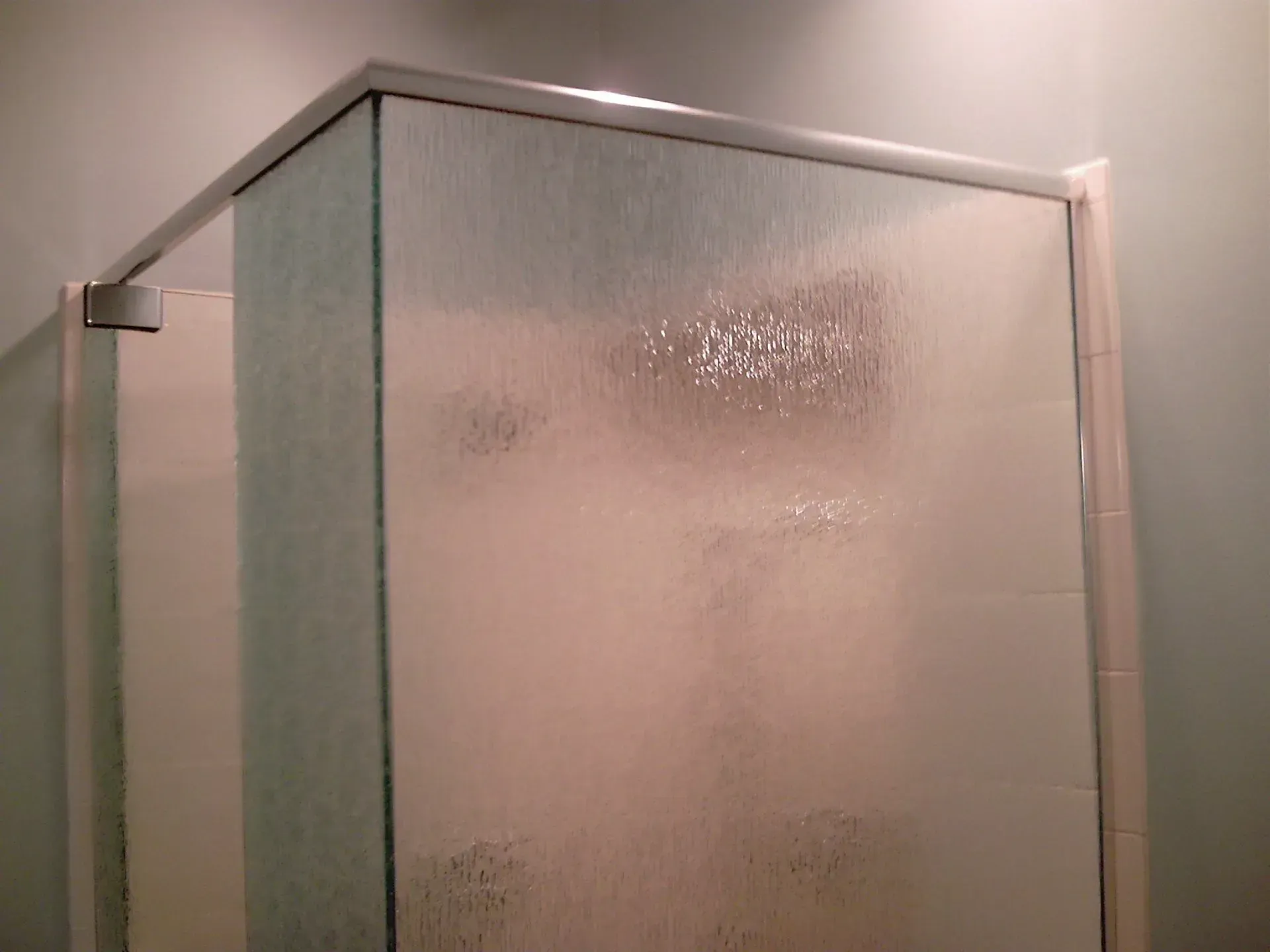 Frosted glass shower enclosure with silver framing in a bathroom.