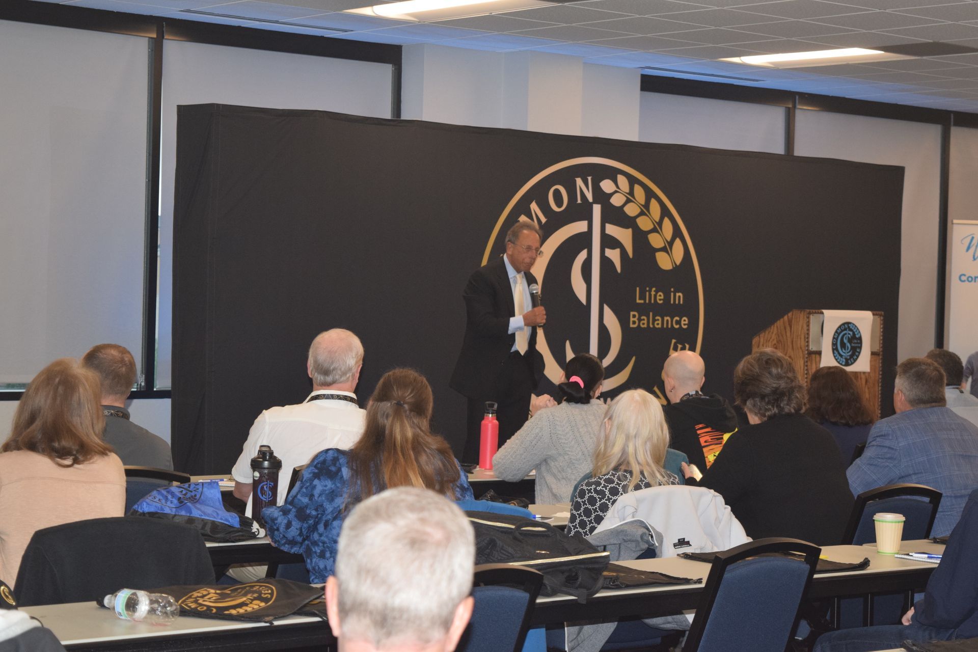 A man is giving a presentation to a group of people sitting at tables.
