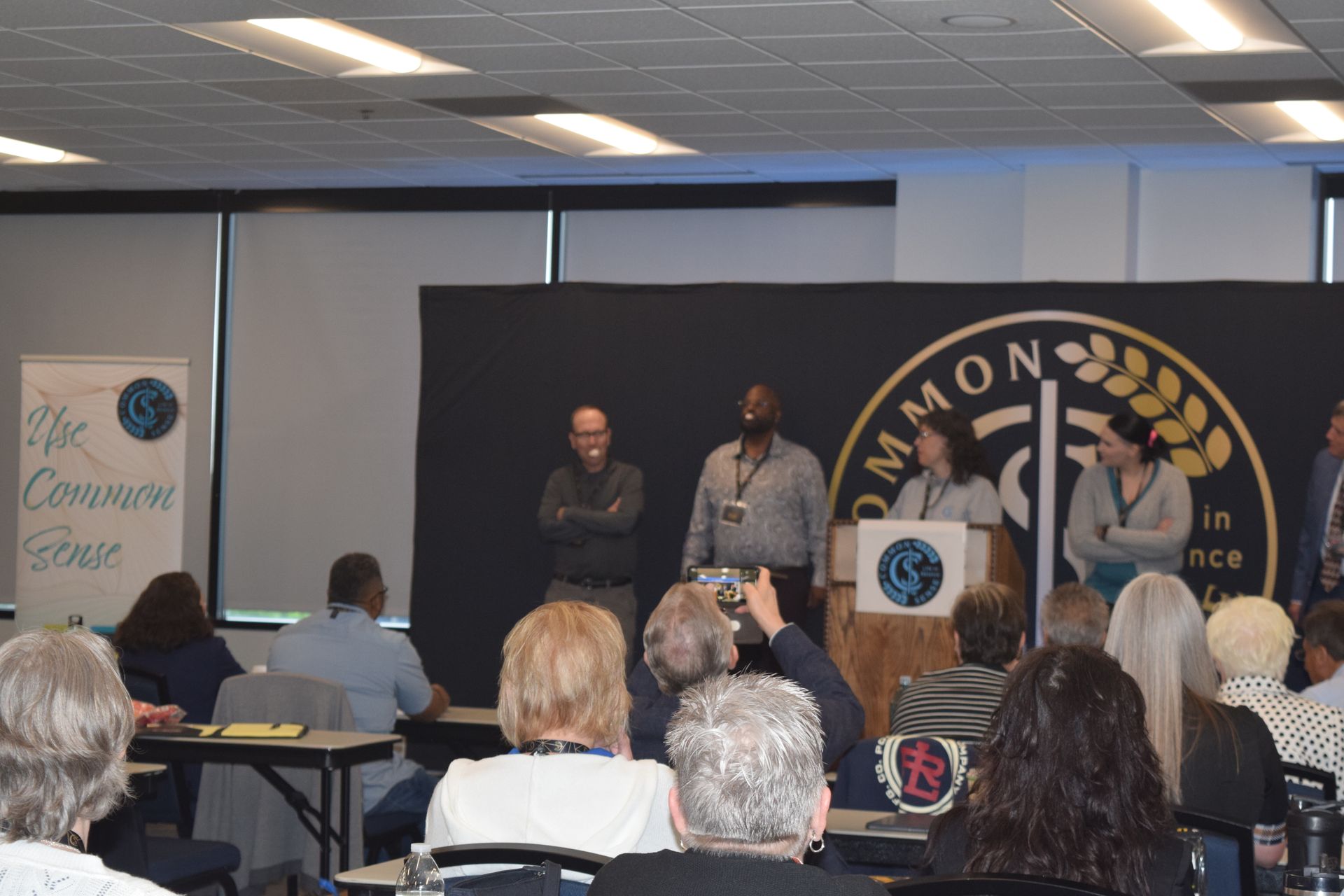 A group of people are sitting in front of a podium that says common science