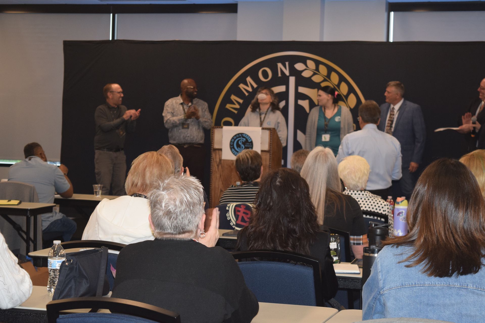 A group of people are sitting at tables in front of a podium.