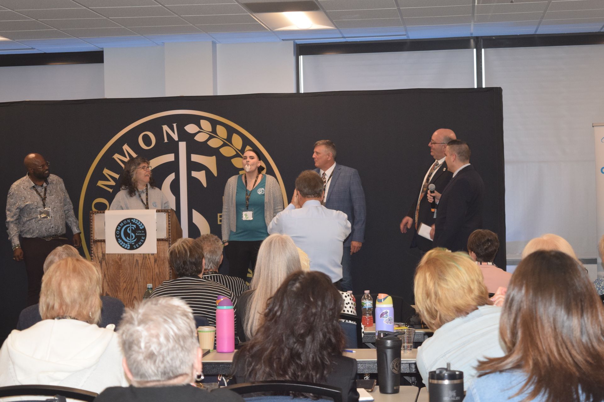 A group of people are sitting at tables in front of a podium.