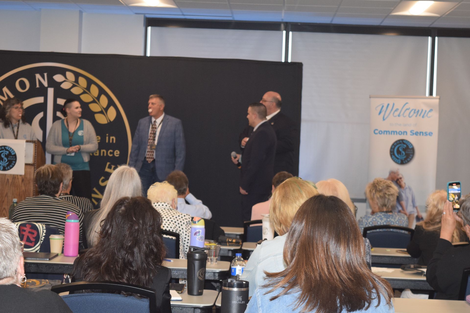 A group of people are sitting at tables in a conference room.