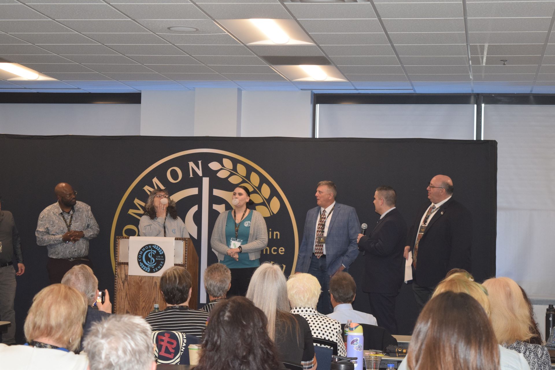 A group of people standing in front of a podium with the word common on it