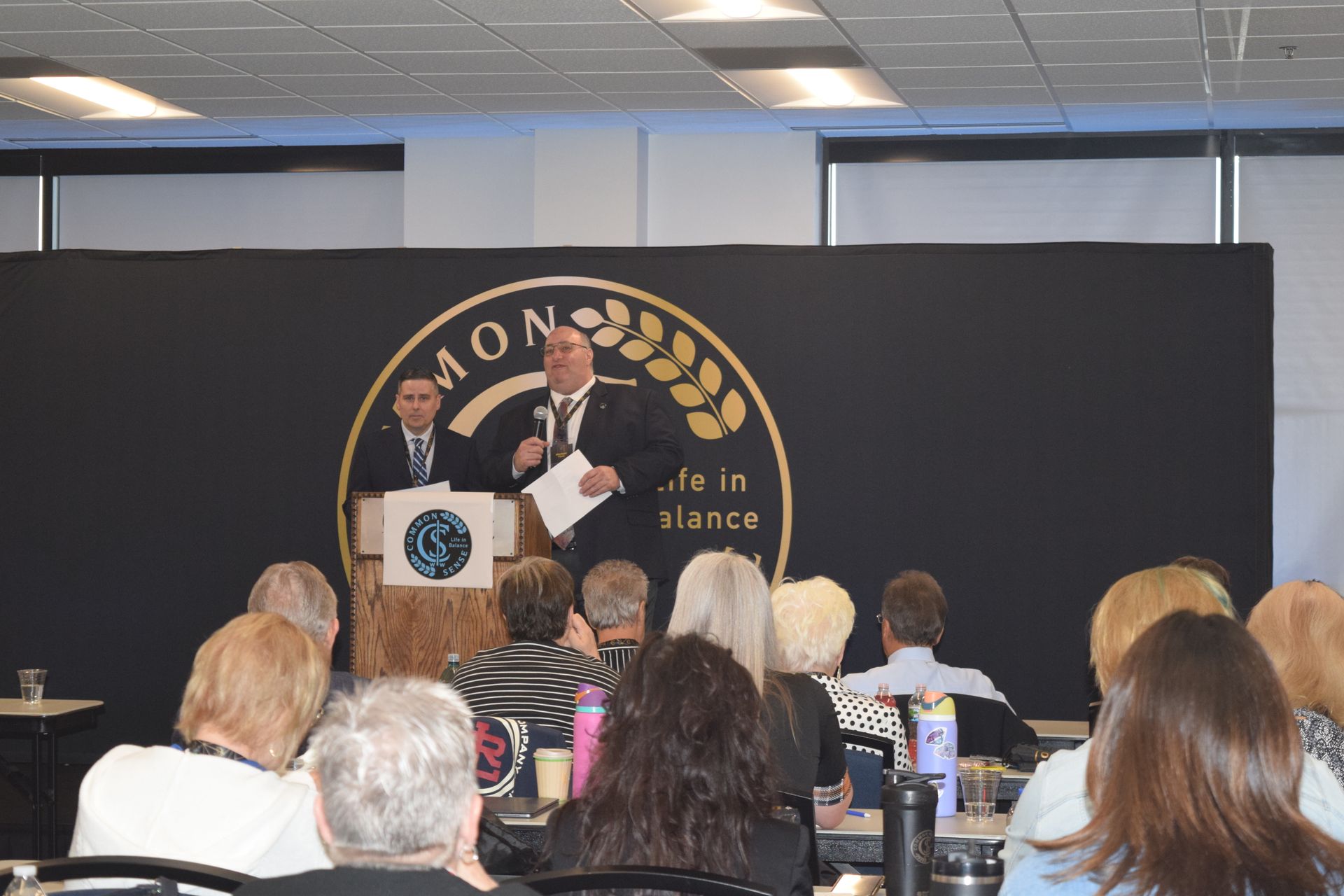 A man stands at a podium giving a speech to a group of people