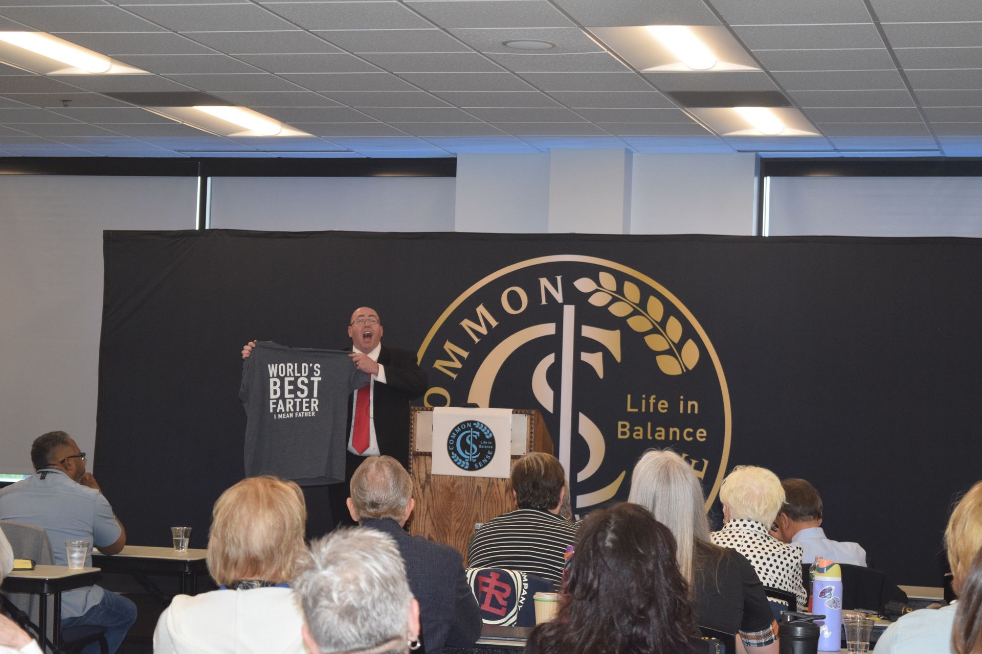 A man stands at a podium giving a speech to a group of people