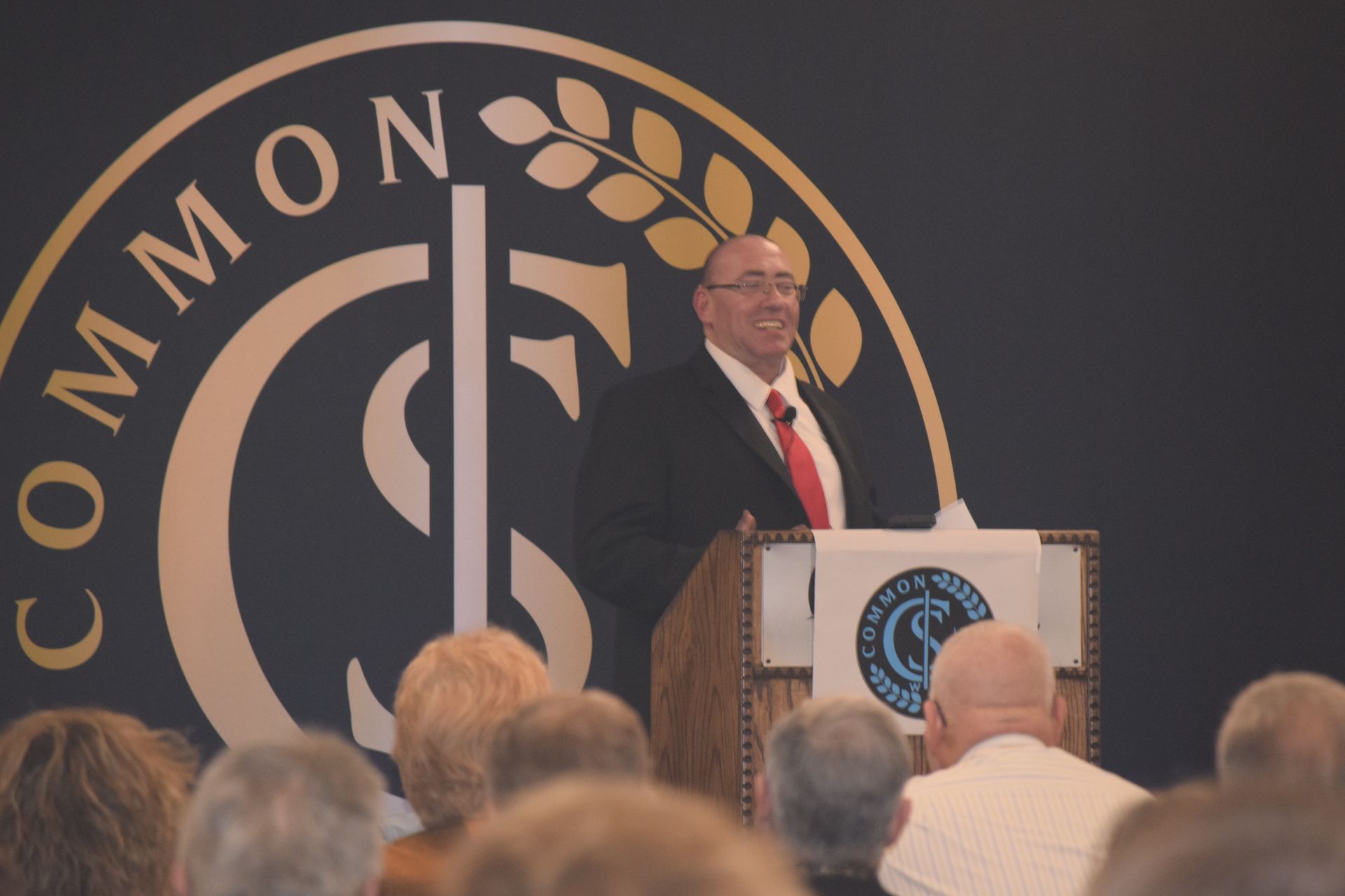 A man stands at a podium in front of a sign that says common