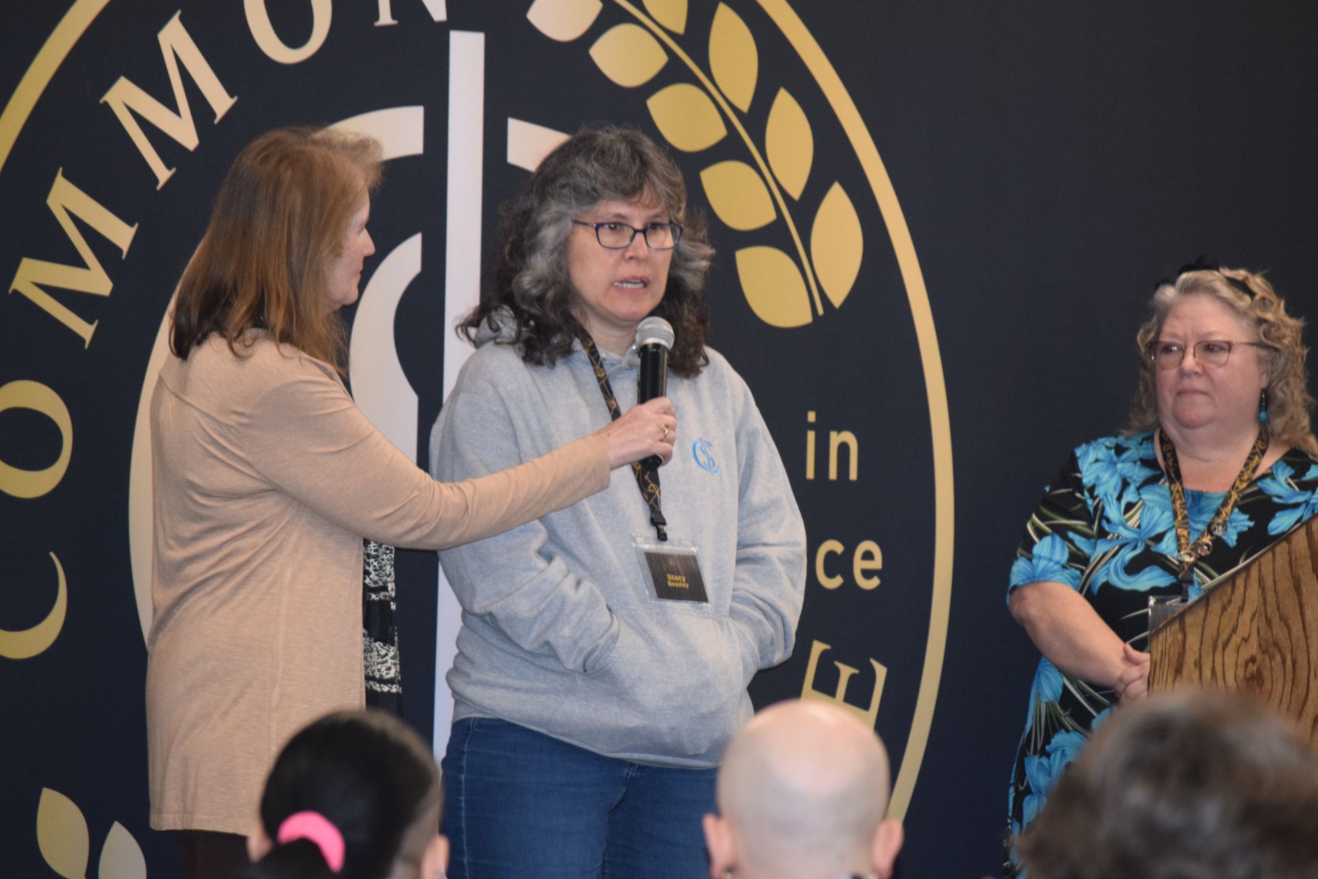 A woman is speaking into a microphone in front of a crowd of people.