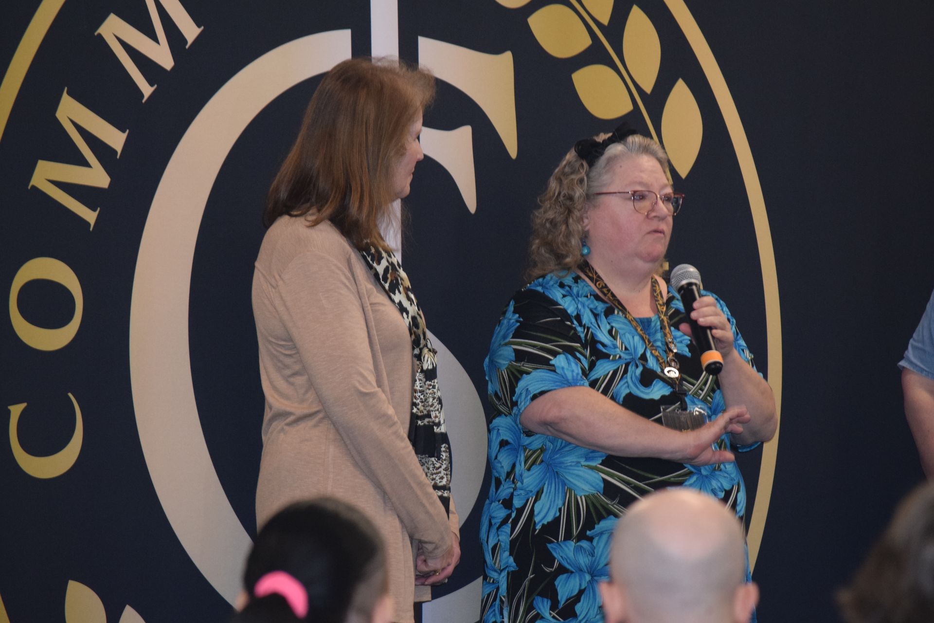 Two women are standing in front of a sign that says comm