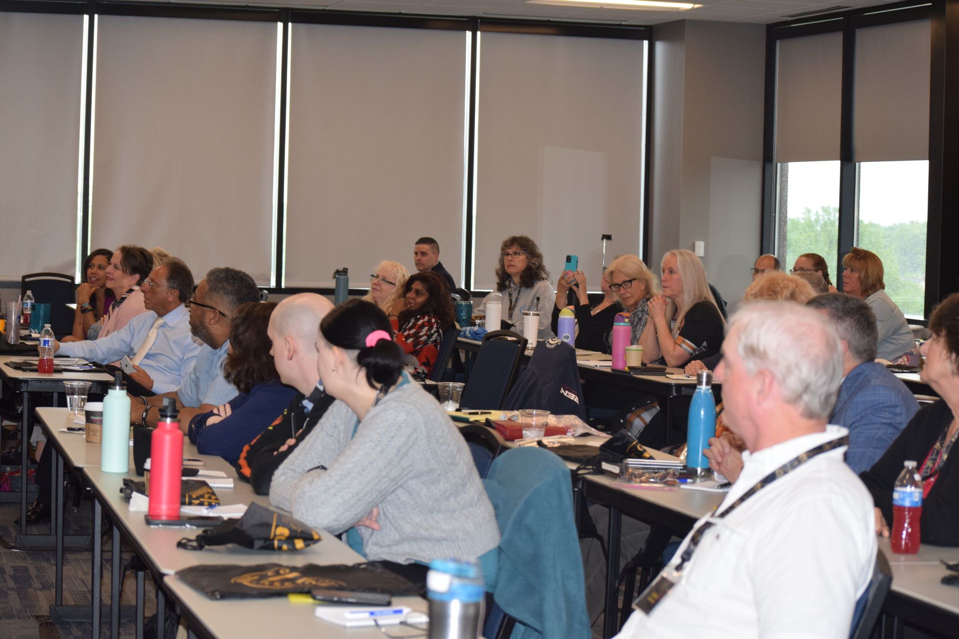 A group of people are sitting at tables in a classroom.