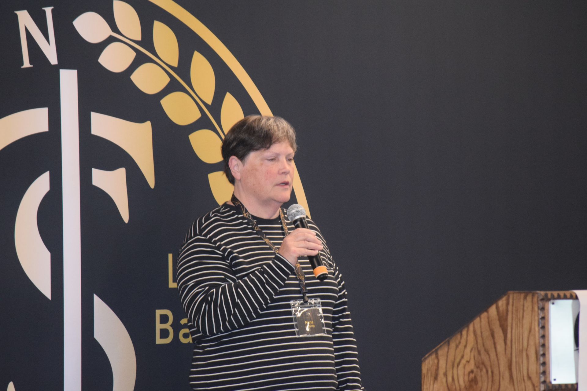 A woman is standing at a podium holding a microphone.