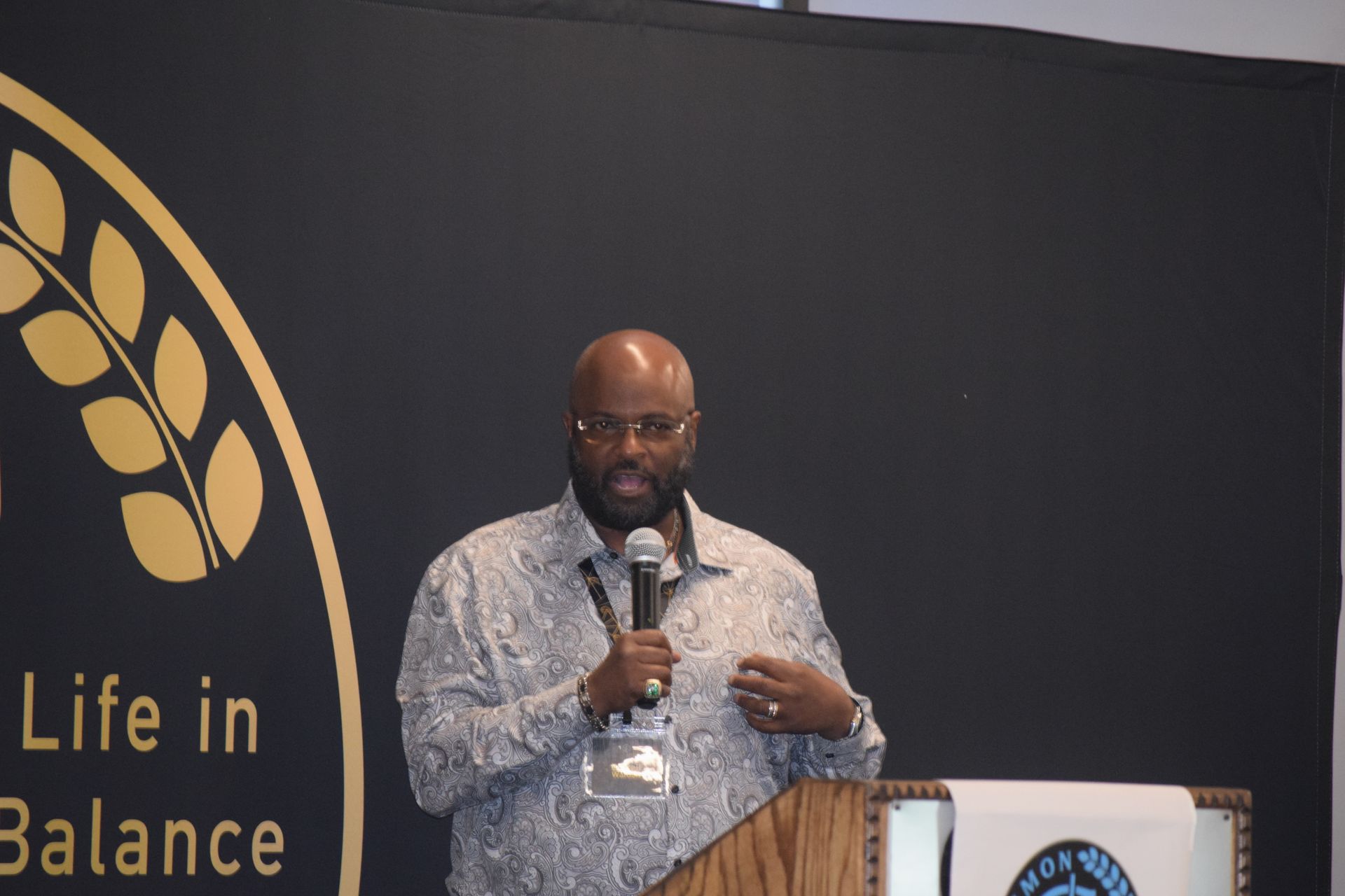 A man is standing at a podium holding a microphone.