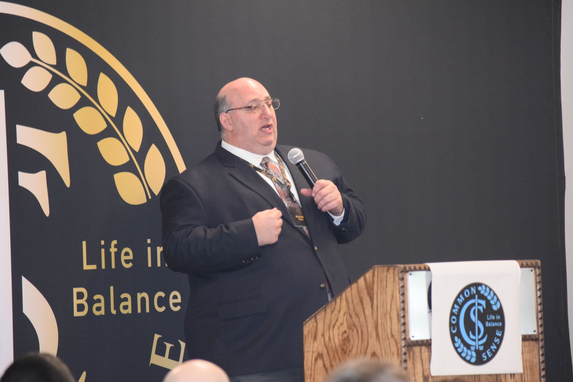 A man stands at a podium with a sign that says life in balance