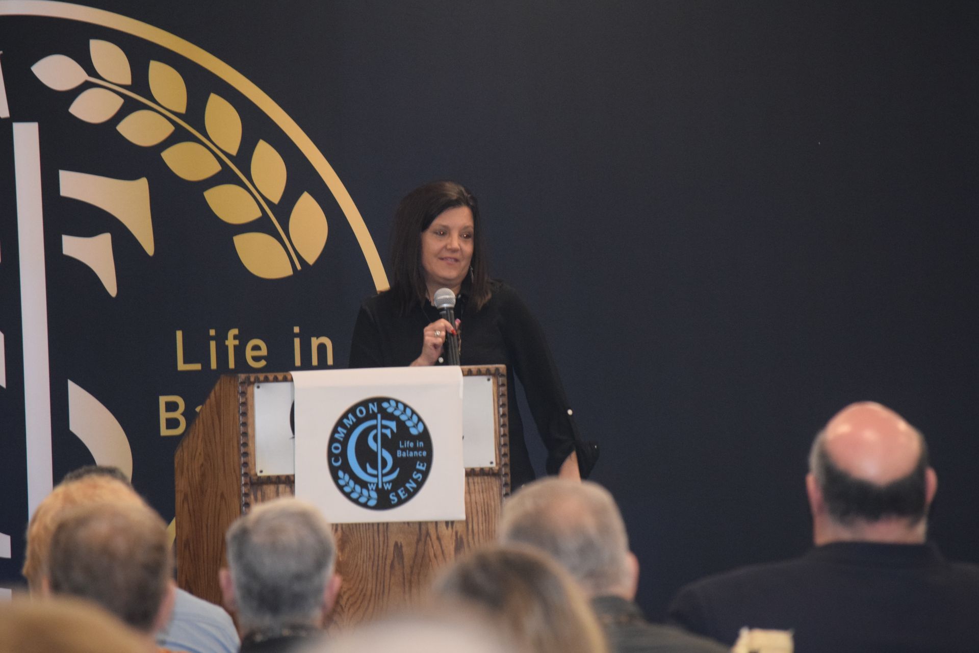 A woman stands at a podium with a sign that says life in