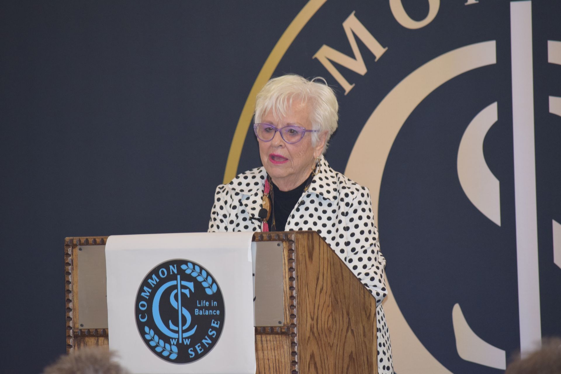A woman is giving a speech at a podium in front of a sign that says common sense