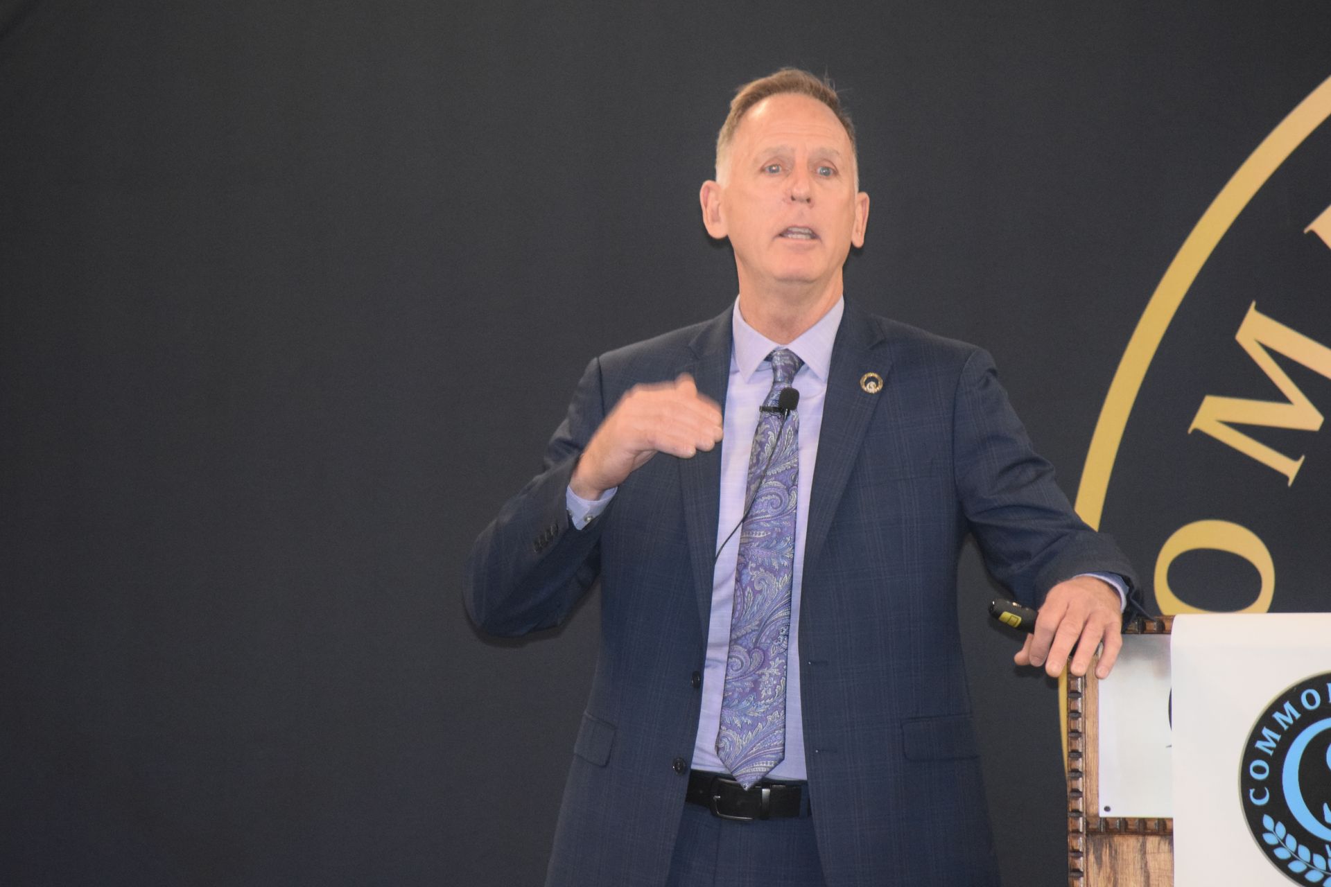 A man in a suit and tie is giving a speech at a podium.