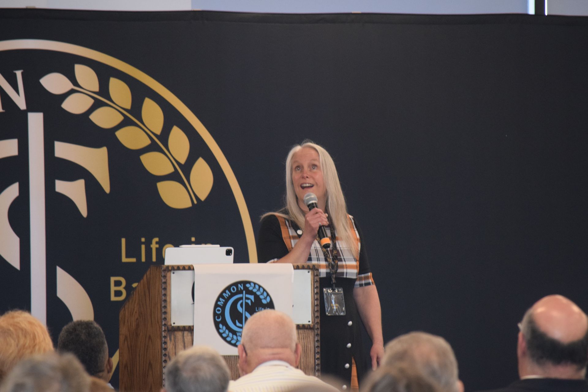 A woman stands at a podium speaking into a microphone