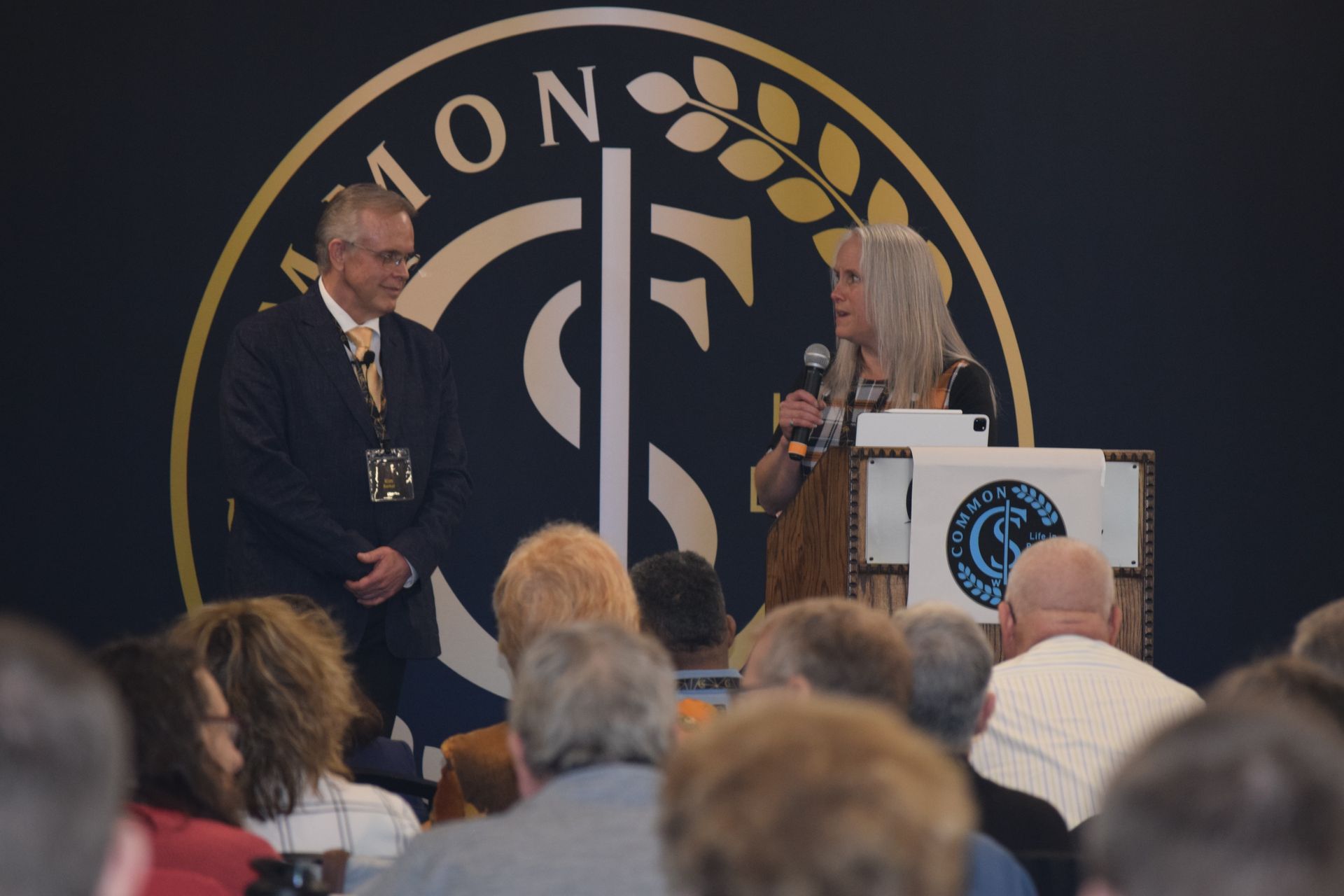 A man and a woman are standing in front of a crowd of people.