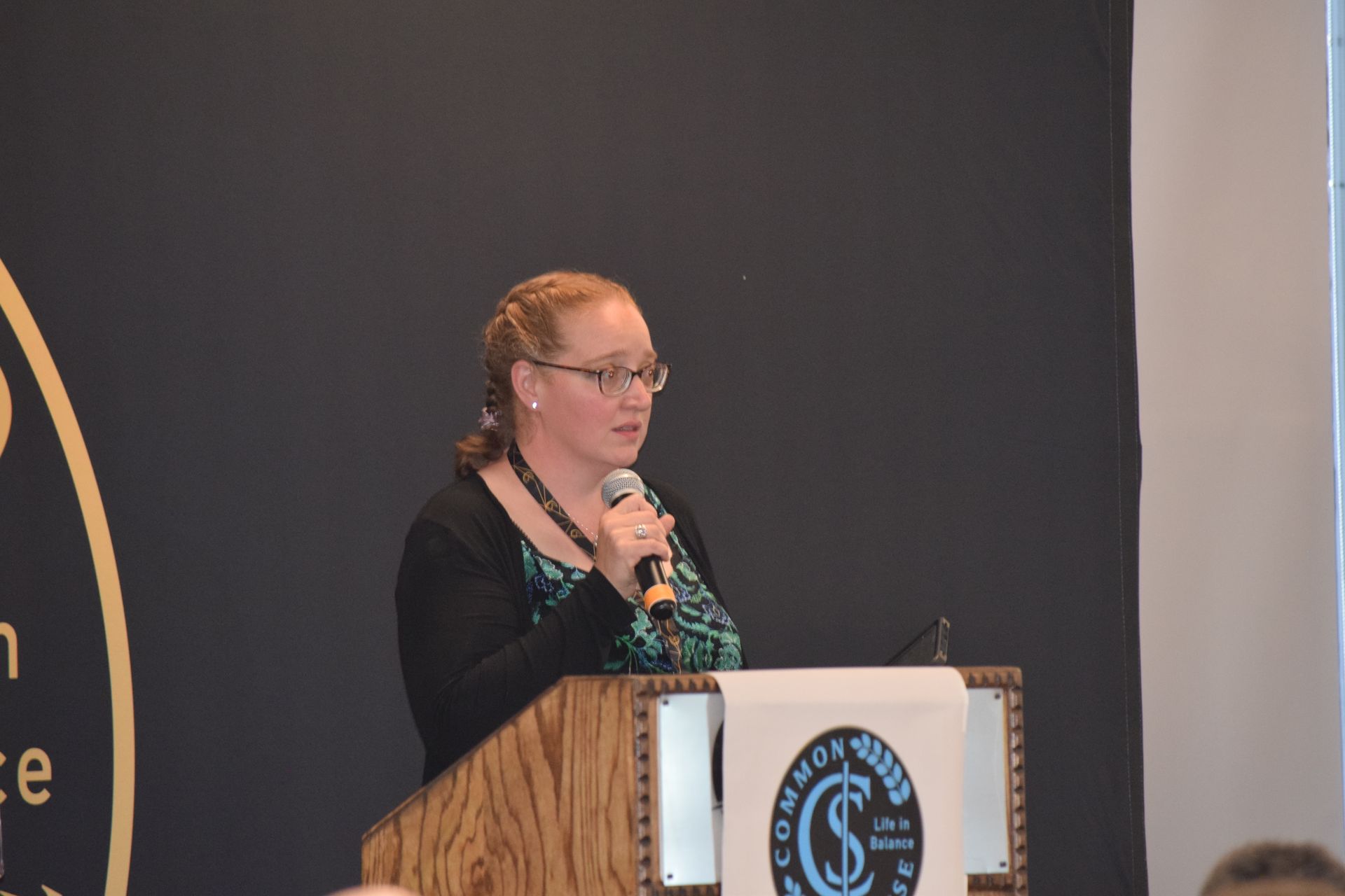 A woman is standing at a podium speaking into a microphone.