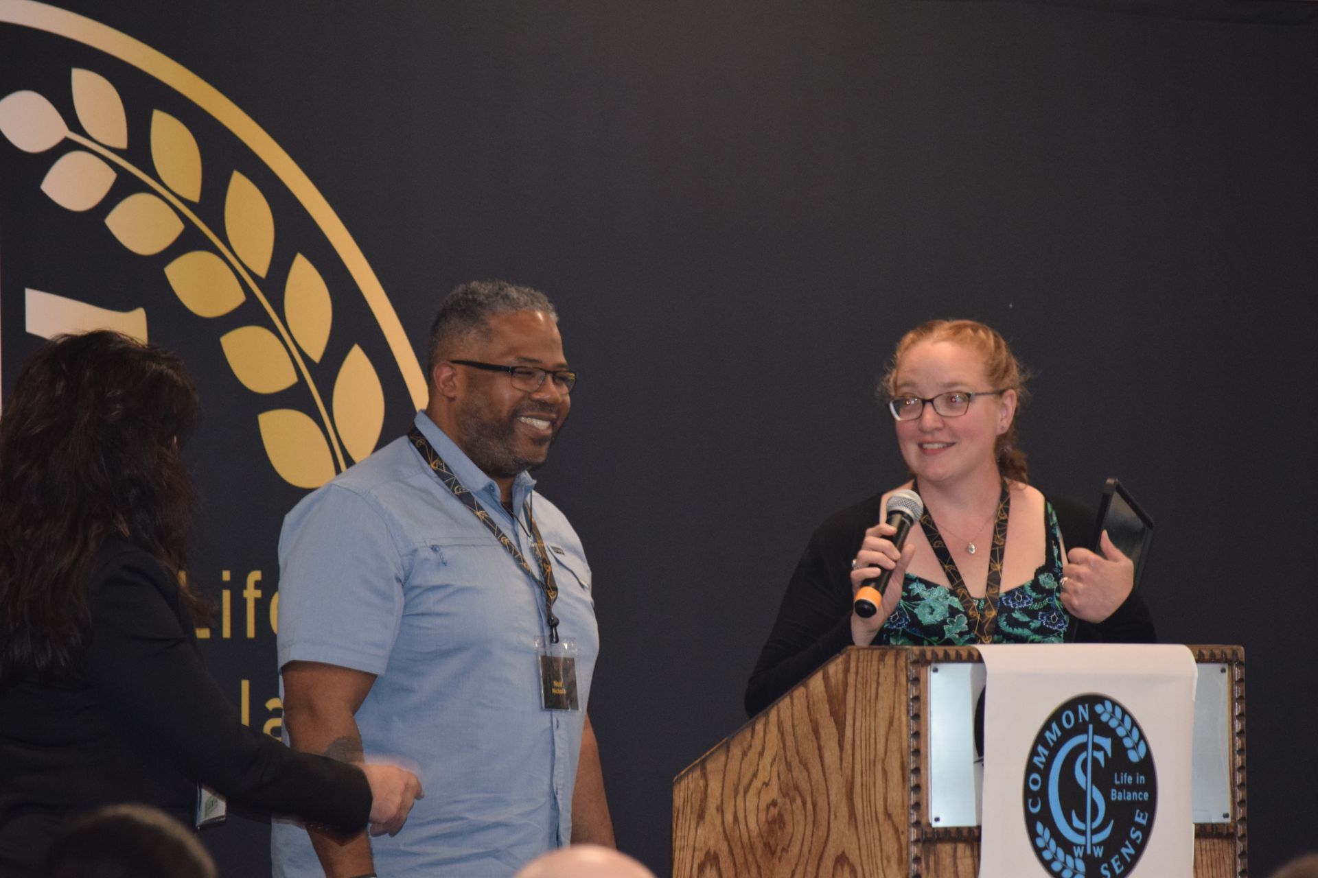A man and a woman are standing at a podium holding microphones.