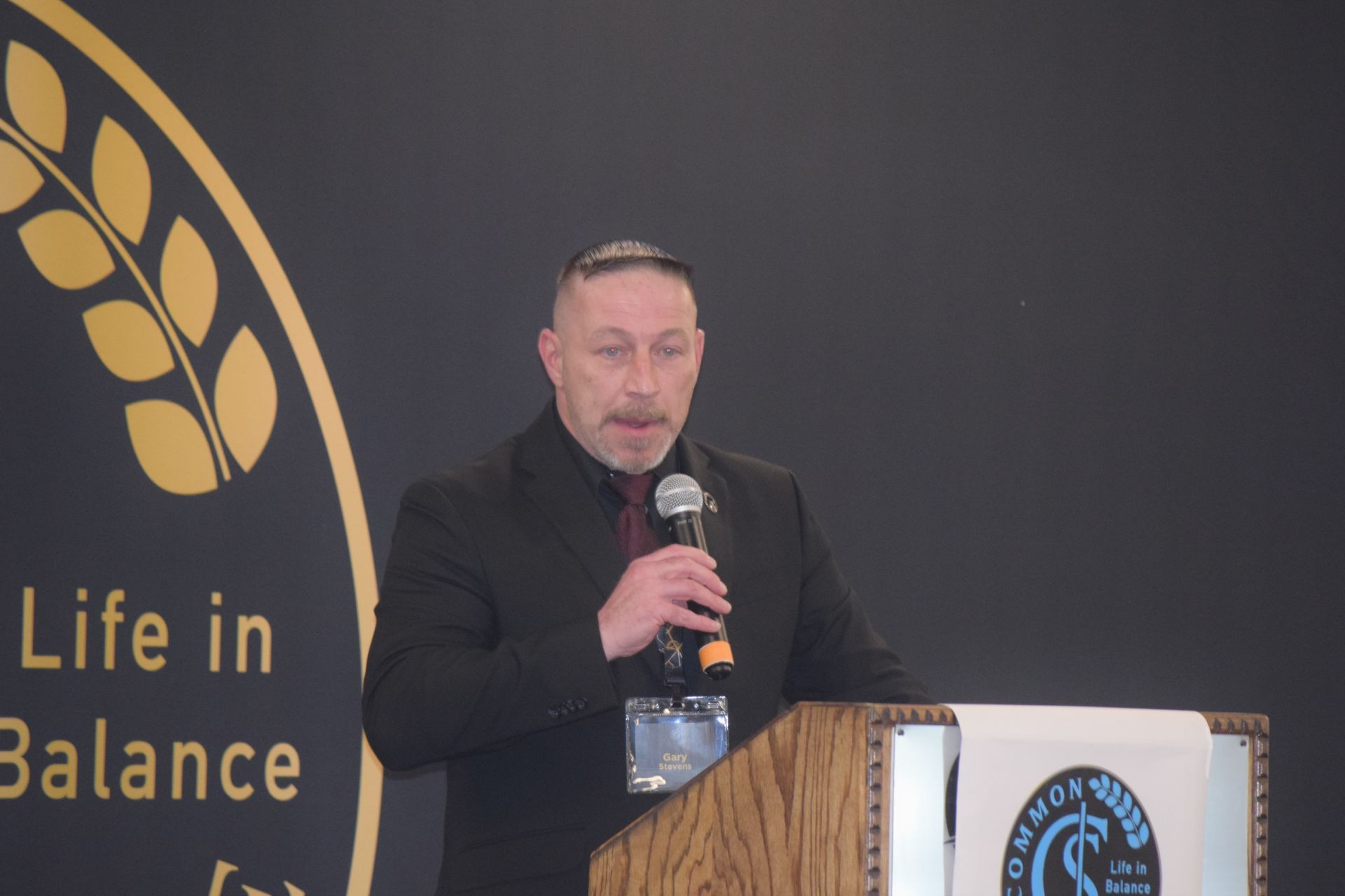 A man is standing at a podium holding a microphone.